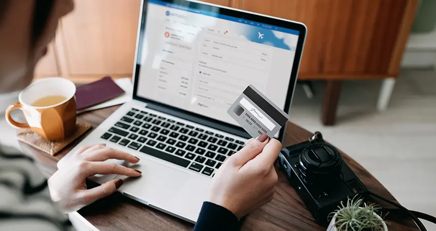 woman on laptop holding debit card