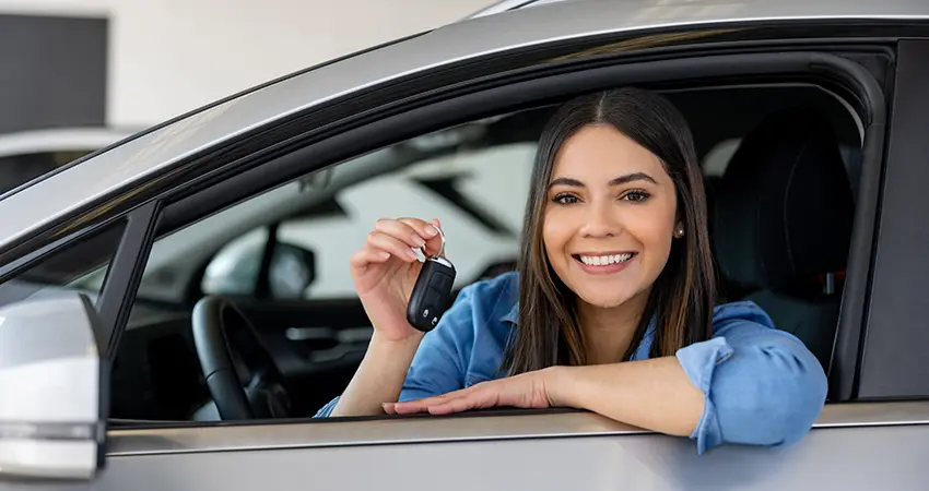 smiling woman in new car holding keys